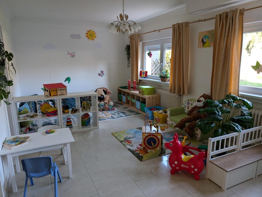 Blick in den Gruppenraum mit Maltisch, Regal, Sofa und Hüpfpferd